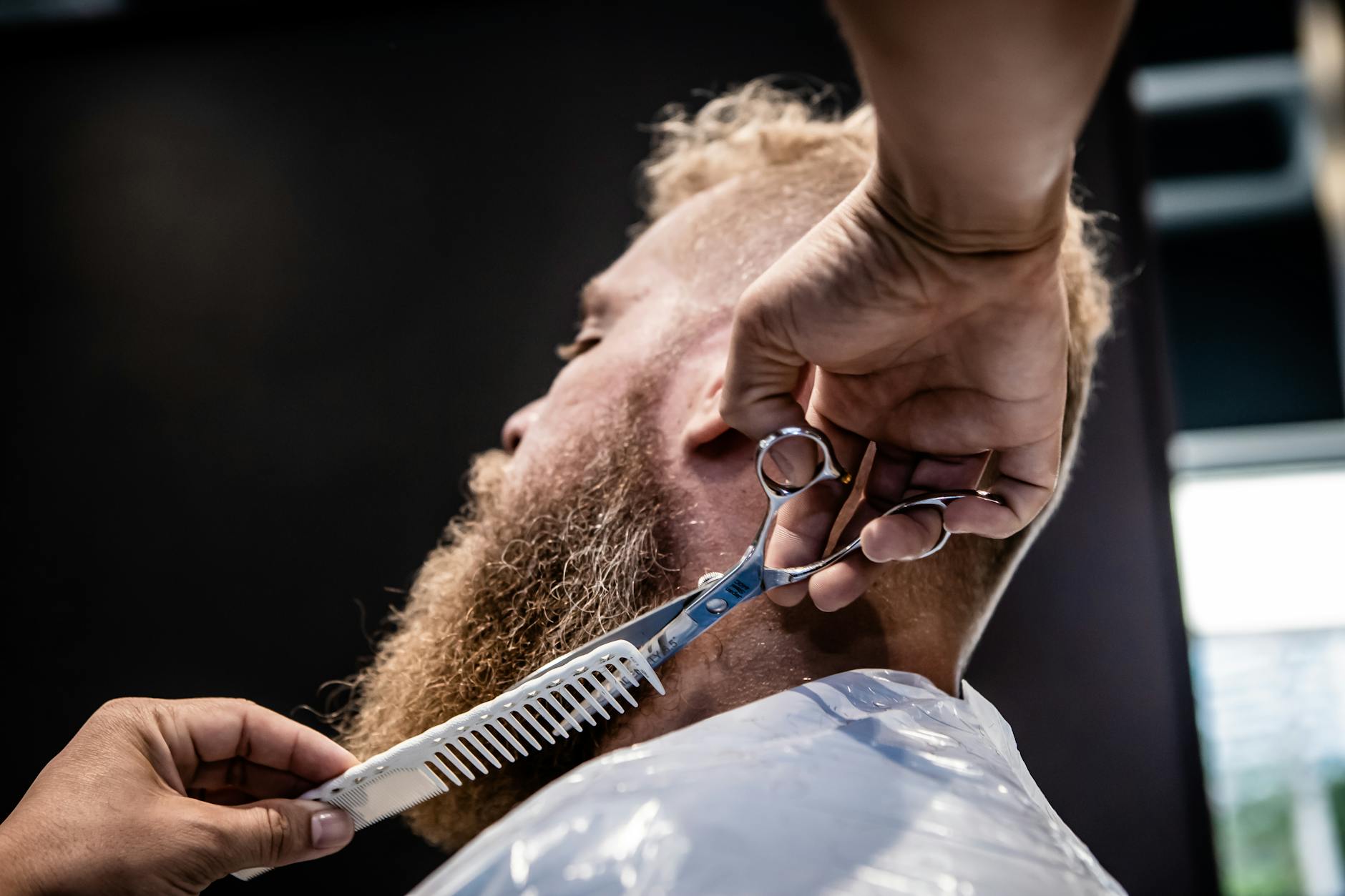 Close-up of a barber trimming a beard with scissors